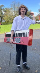 mann med halvlangt mørkt hår med et keyboard under armen