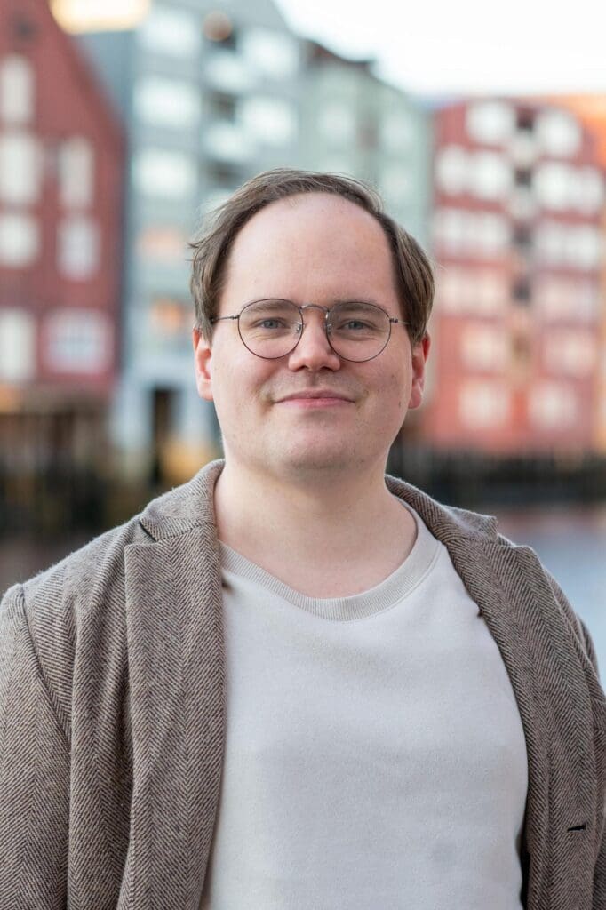 mann med mørkt hår, by i bakgrunnen