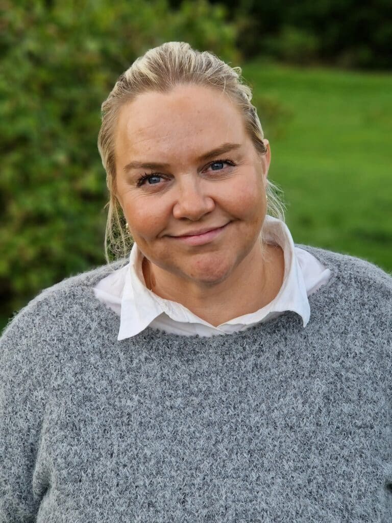 kvinne med lyst hår og grå genser
